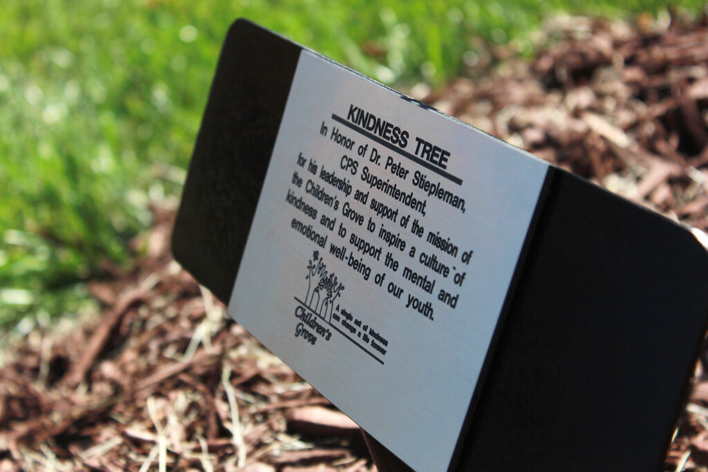 The dedication plaque created in honor of Peter Stiepleman is revealed during the Children's Grove kindness tree ceremony